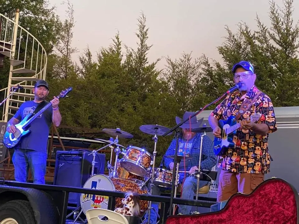 All three members of the Clay Potter Band playing an evening set under stage lights All three members of the Clay Potter Band playing an evening set under stage lights