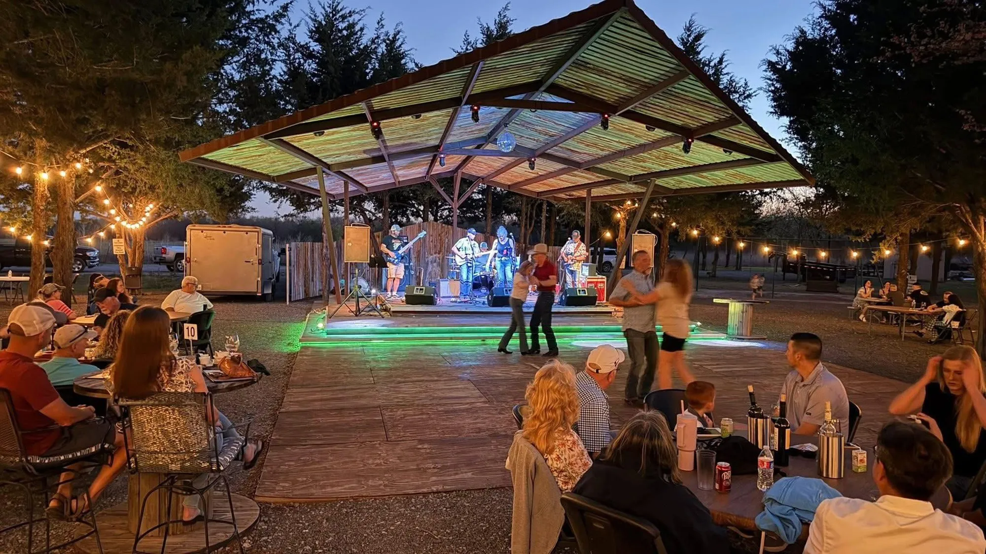 Clay Potter Band playing under an open-air pavilion at dusk as couples dance and the crowd fills string-lit tables Clay Potter Band playing under an open-air pavilion at dusk as couples dance and the crowd fills string-lit tables