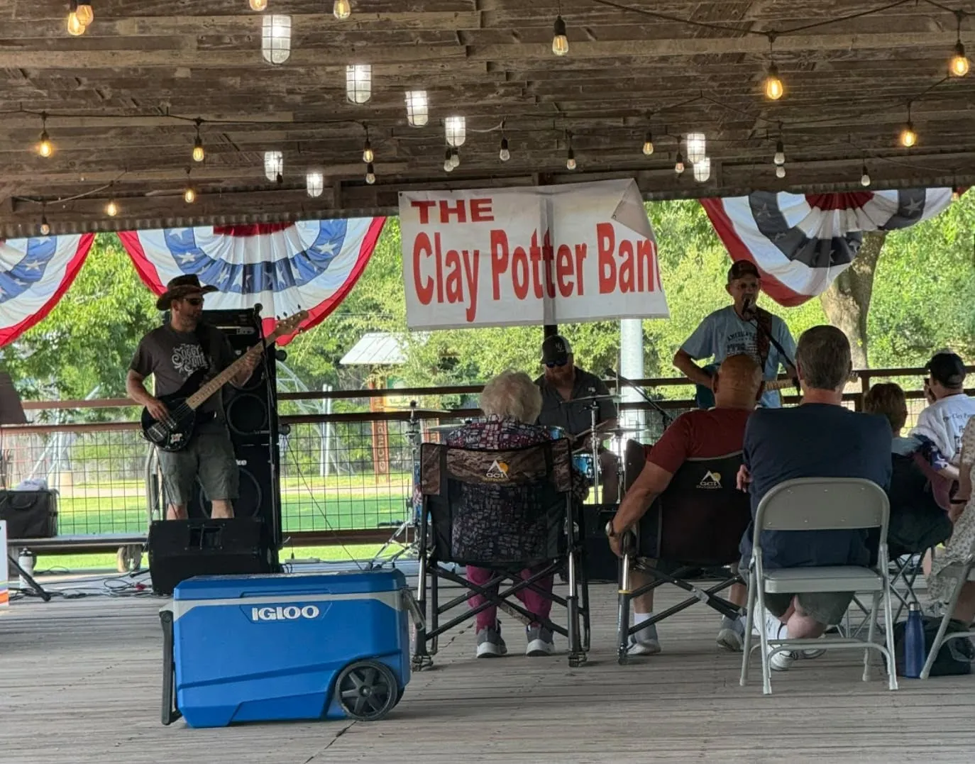 The Clay Potter Band banner hung under a patriotic-draped pavilion as the band plays for a seated crowd The Clay Potter Band banner hung under a patriotic-draped pavilion as the band plays for a seated crowd